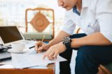 Administrator businessman making report, calculating balance. Business analyzing income charts, graphs and data on the table.