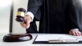 Male Judge lawyer In A Courtroom Striking The Gavel on sounding block.
