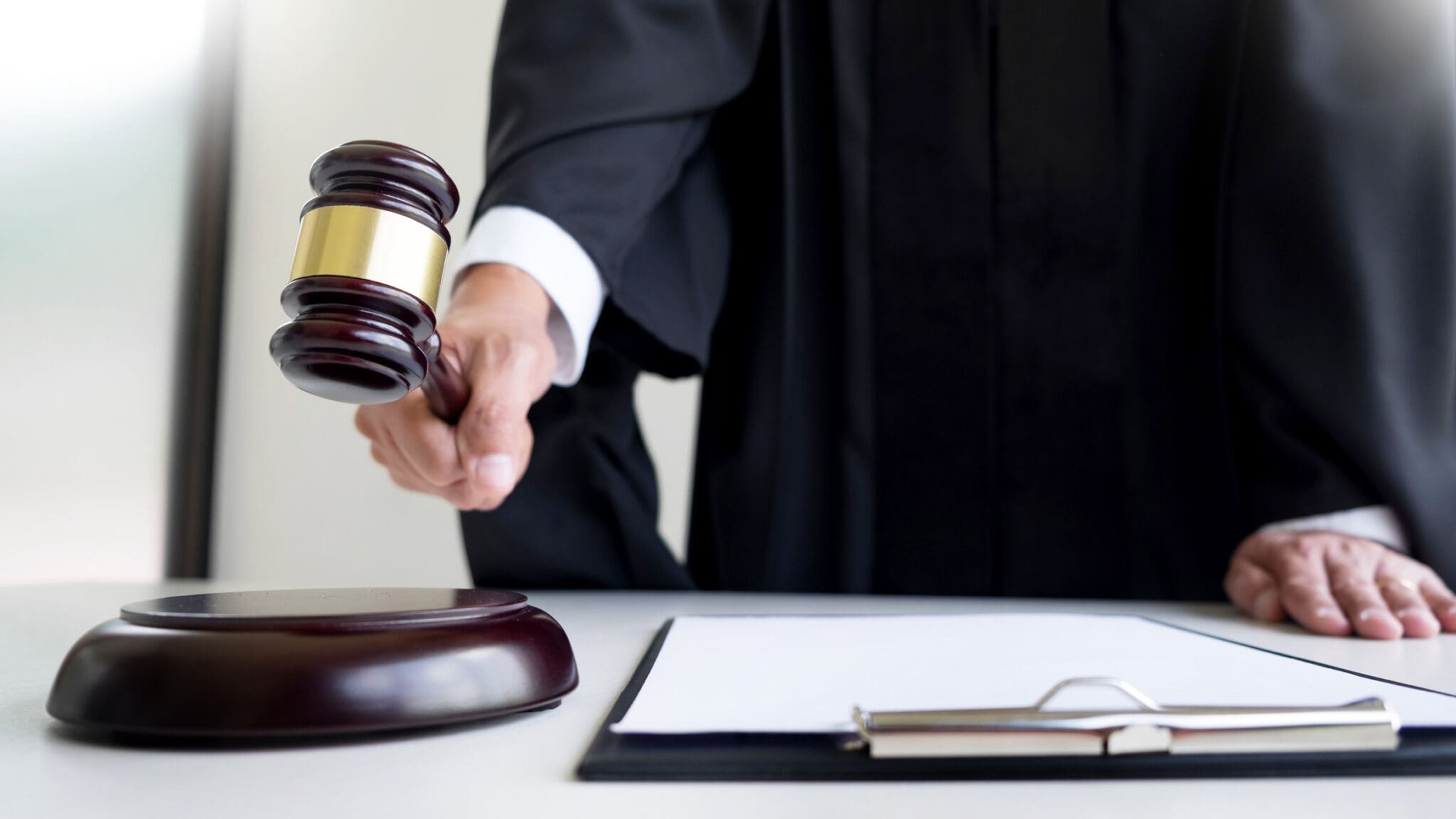 Male Judge lawyer In A Courtroom Striking The Gavel on sounding block.
